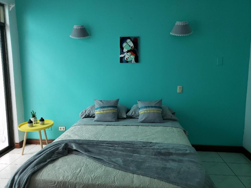 a blue bedroom with a bed and a yellow table at La Casa Azul in Alajuela