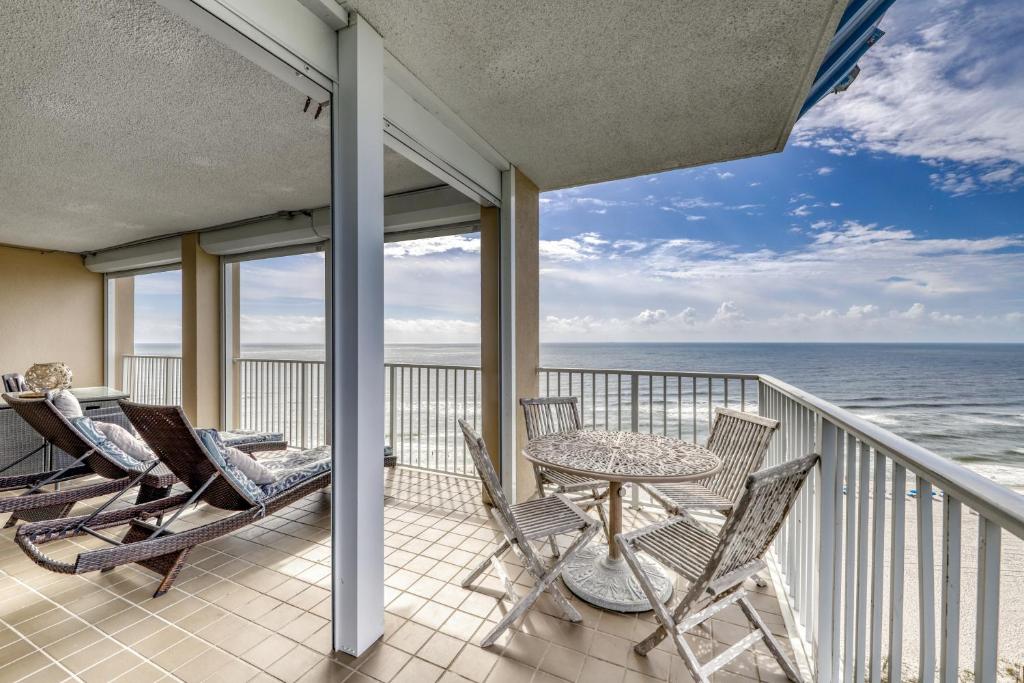 a balcony with chairs and a table and the ocean at Bluewater Apartments in Orange Beach