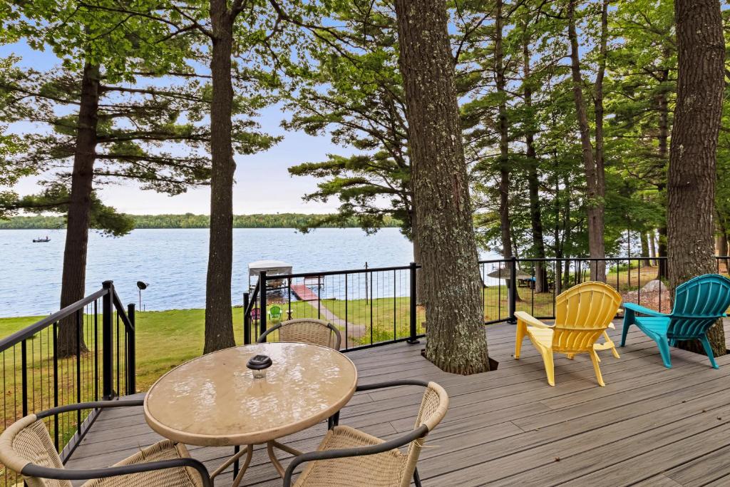 a table and chairs on a wooden deck with a view of the water at Artist's Cove in Manitowish Waters