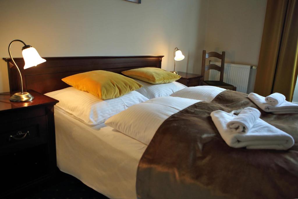 a large bed with two towels and two robes at Pałac Spichrz in Borcz