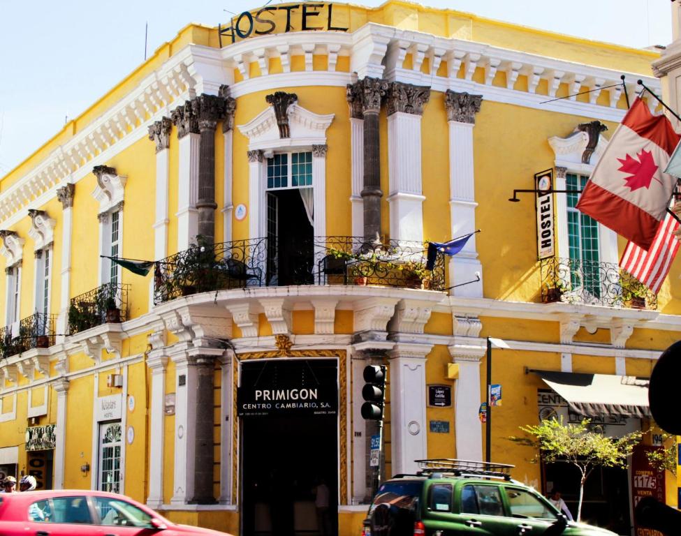 um edifício amarelo com carros estacionados em frente em Hostel Hospedarte Centro em Guadalajara