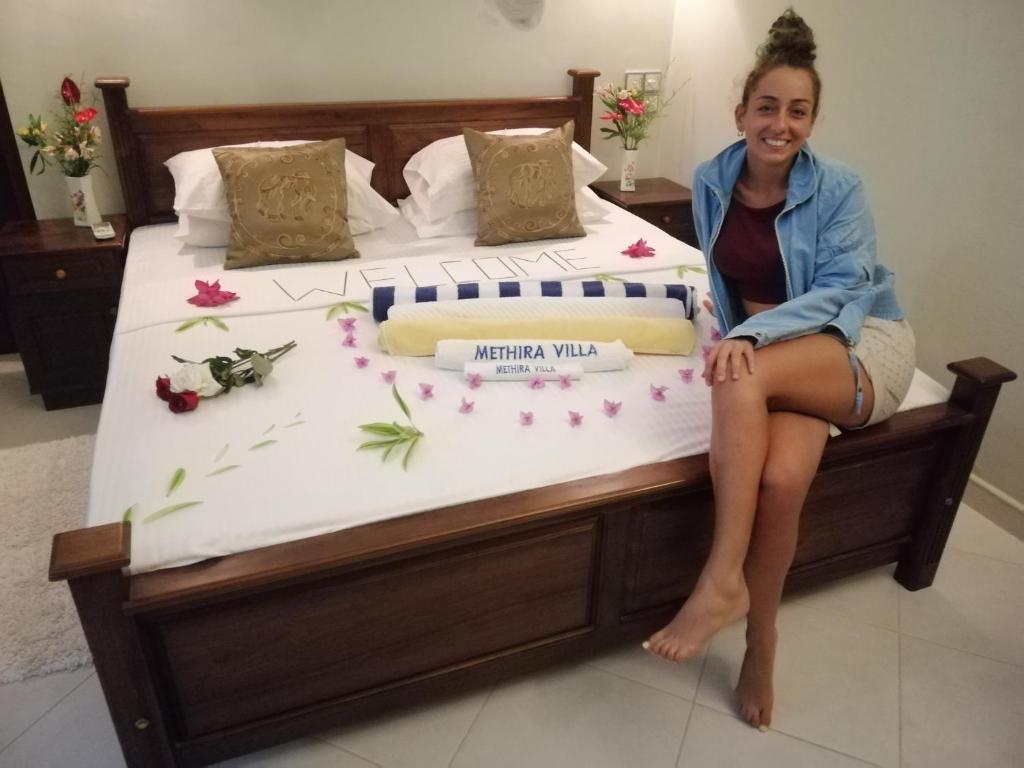 a woman is sitting on a large bed at Methira Villa in Aluthgama