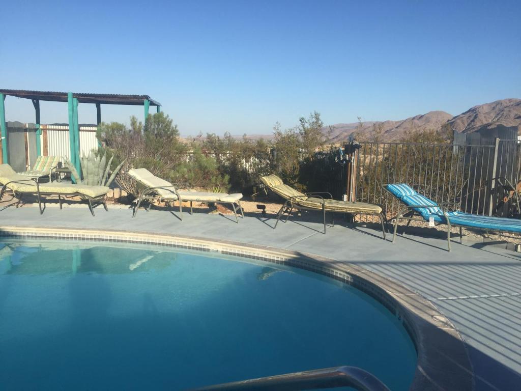 een zwembad met stoelen en een tafel en stoelen bij Harmony Motel in Twentynine Palms