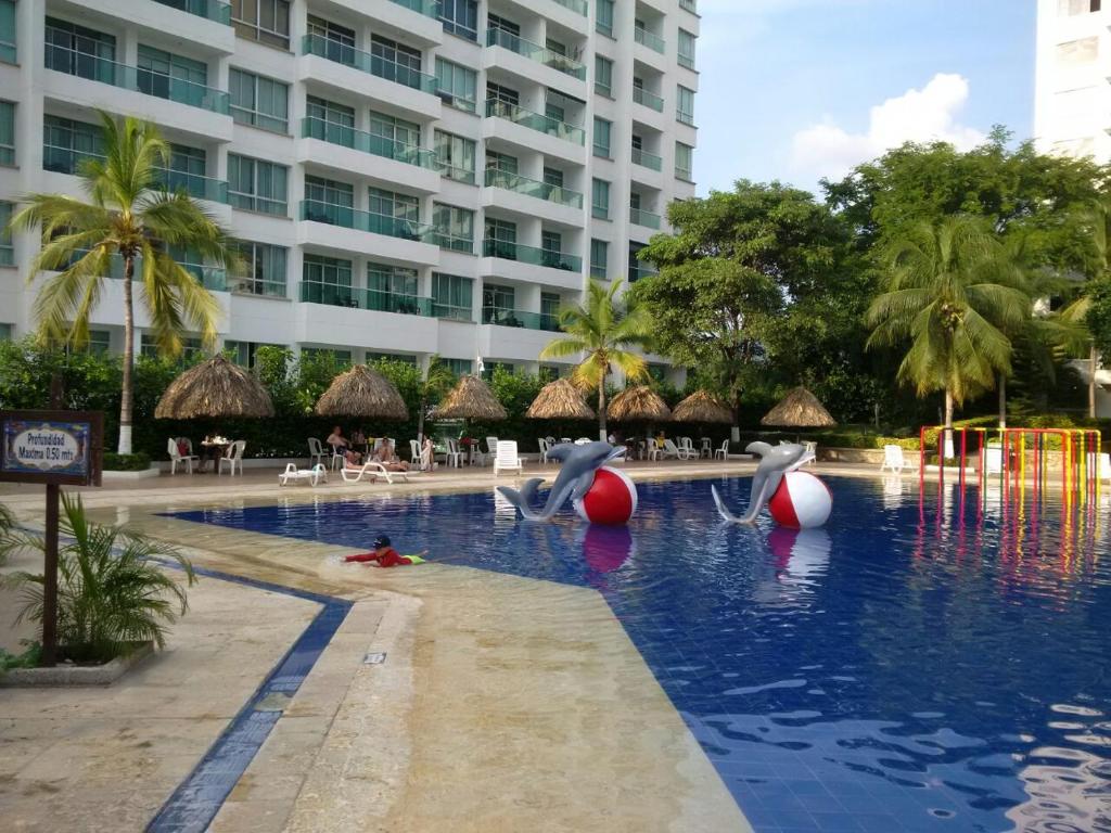 a resort swimming pool with dolphins in the water at Costa Azul Suites Apartamento 603 in Santa Marta