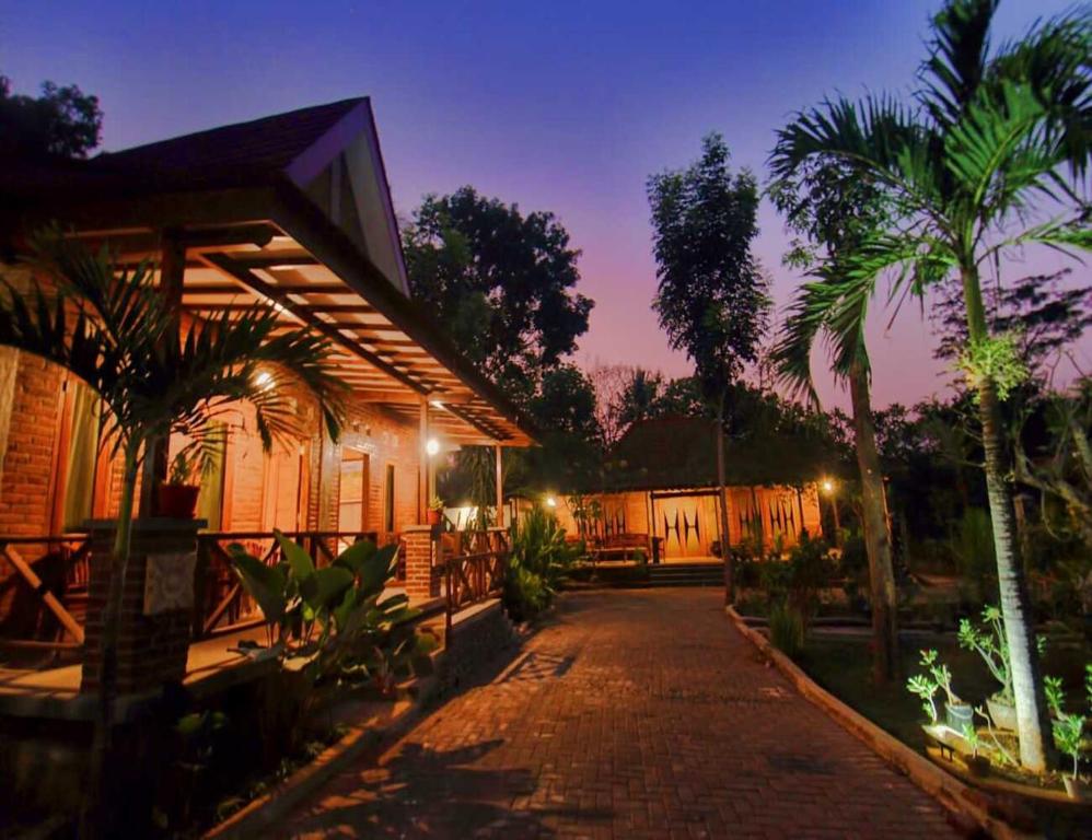 a house with palm trees and a brick driveway at Omah Joglo Semarang in Semarang