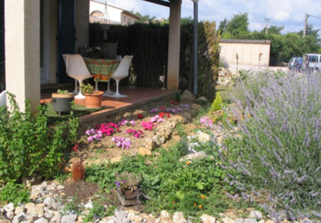 a garden with flowers and chairs on a porch at Les Tourterelles in Callian