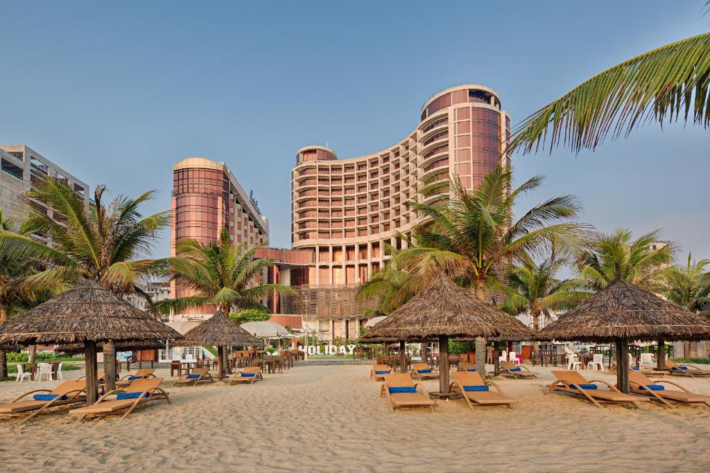 una playa con sillas y palmeras y un hotel en Holiday Beach Hotel Danang, en Da Nang