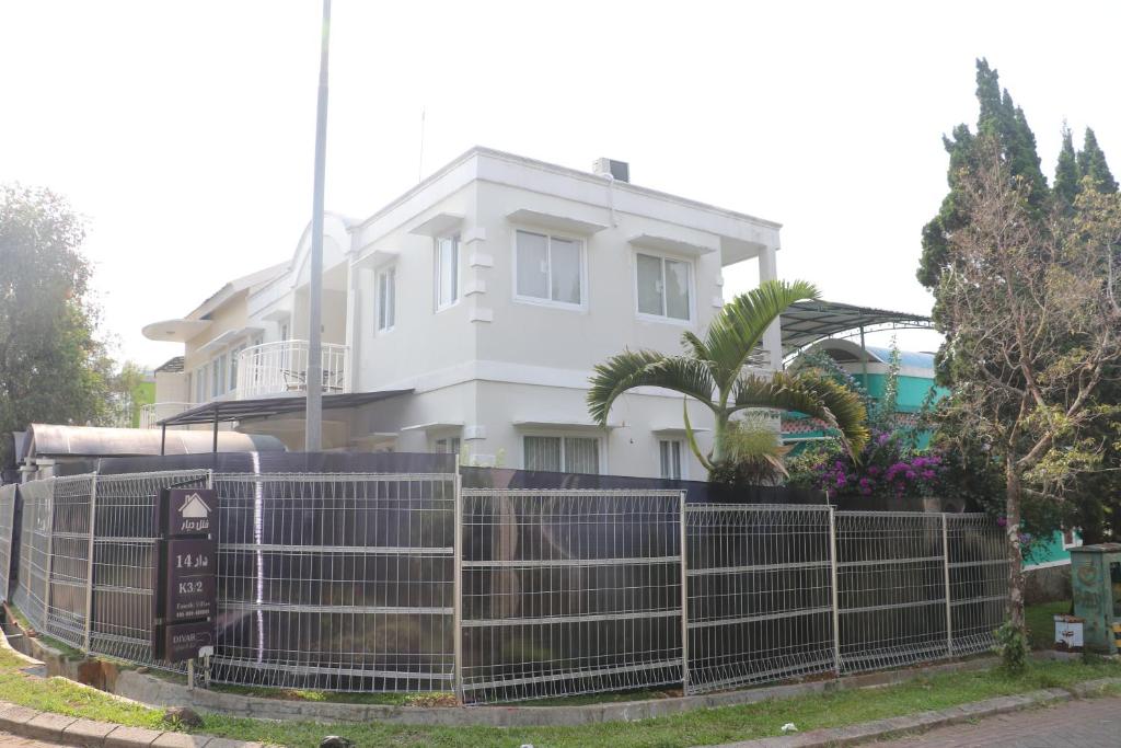 une maison blanche avec une clôture devant elle dans l'établissement Diyar Villas Puncak K3/2, à Puncak