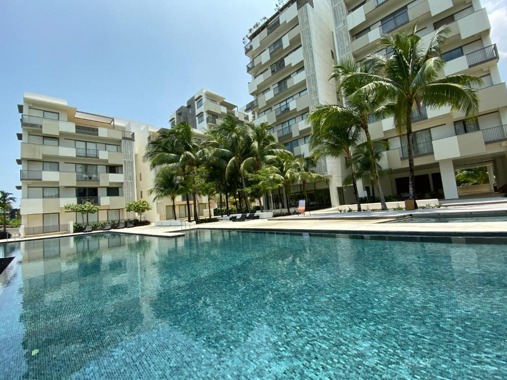 a swimming pool with palm trees and buildings at By The Sea @ Luxury Suites, Batu Ferringhi in Batu Ferringhi