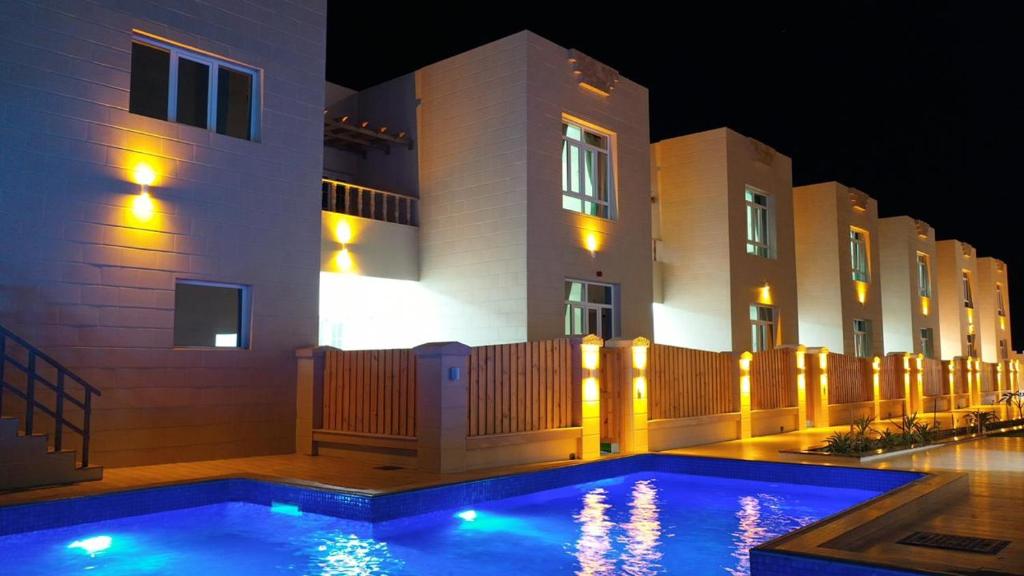 a swimming pool in front of a building at night at Al Asala Resort in Al Ruwis