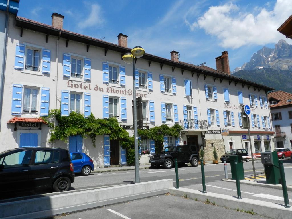 a white building with blue windows on a street at Hotel du Mont Blanc in Sallanches