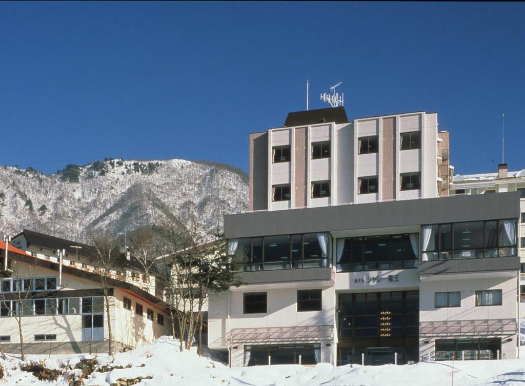 a large building with a mountain in the background at Hotel Chalet Ryuo in Yamanouchi