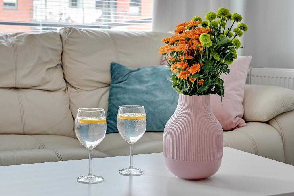 two glasses of water and a vase with flowers on a table at Chmielna Park 5 TriApart® in Gdańsk