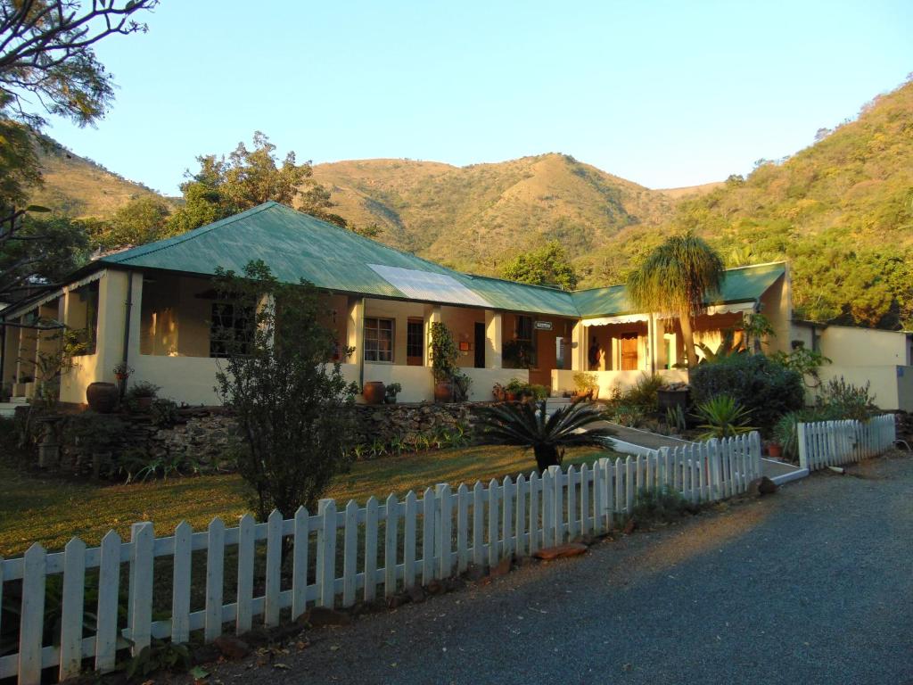 ein Haus mit einem Zaun vor einem Berg in der Unterkunft Fountain Baths Guest Cottages in Barberton