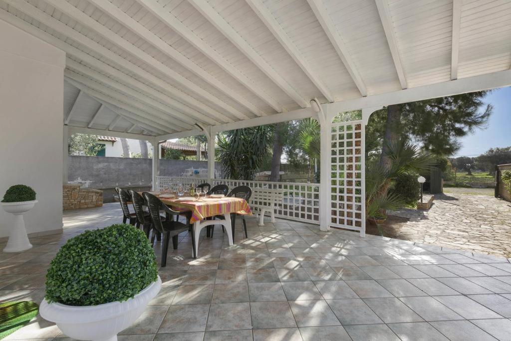 patio con tavolo e sedie sotto un pergolato bianco di Villa LA CAPANNELLA a Nardò