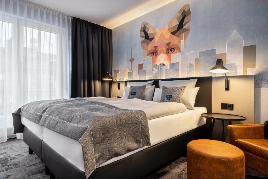 a bedroom with a large bed with a painting on the wall at the niu Charly in Frankfurt