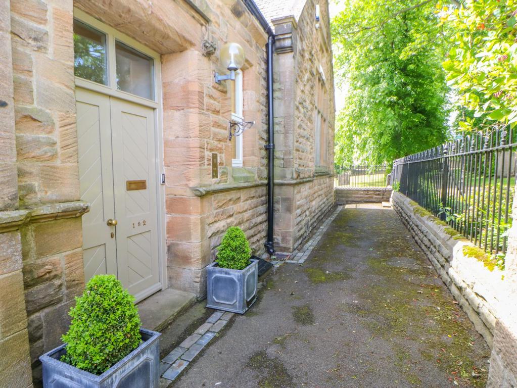 a brick house with a white door and two potted plants at 2 St Marys Close in Barnard Castle