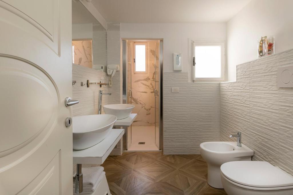 a white bathroom with two sinks and two toilets at Residenza Conte di Cavour & Rooftop in Florence