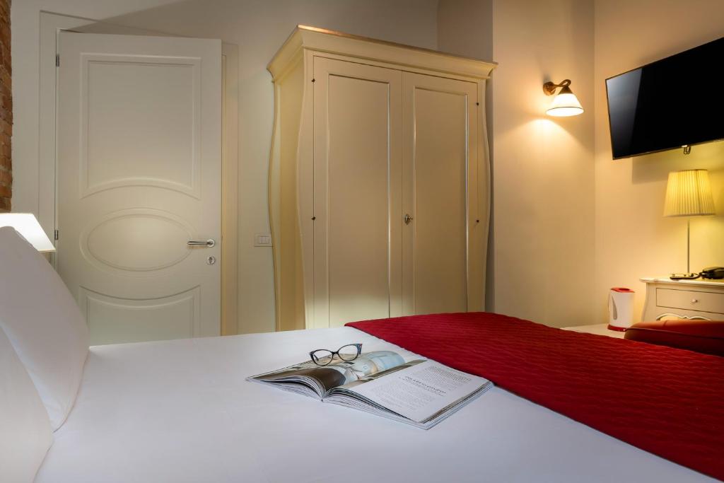 a bed with a book and pair of glasses on it at Residenza Conte di Cavour & Rooftop in Florence