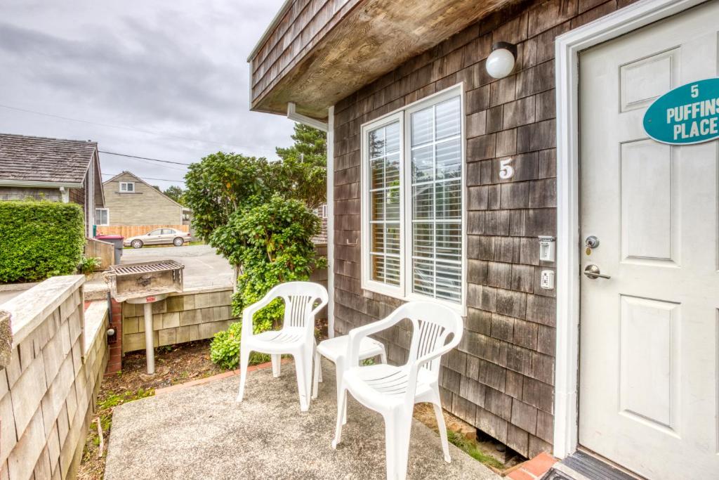 a couple of white chairs sitting on the porch of a house at Beaches Inn | Puffins Place Cabana in Cannon Beach