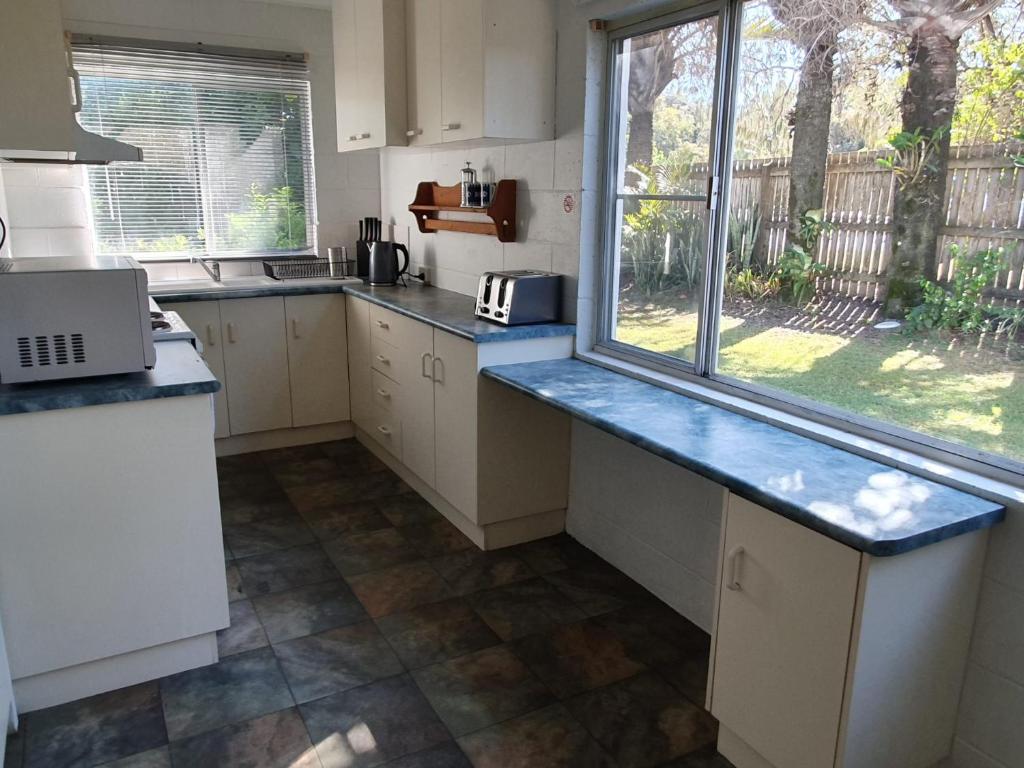 a kitchen with white cabinets and a large window at Number 1 Beach House in Rainbow Beach