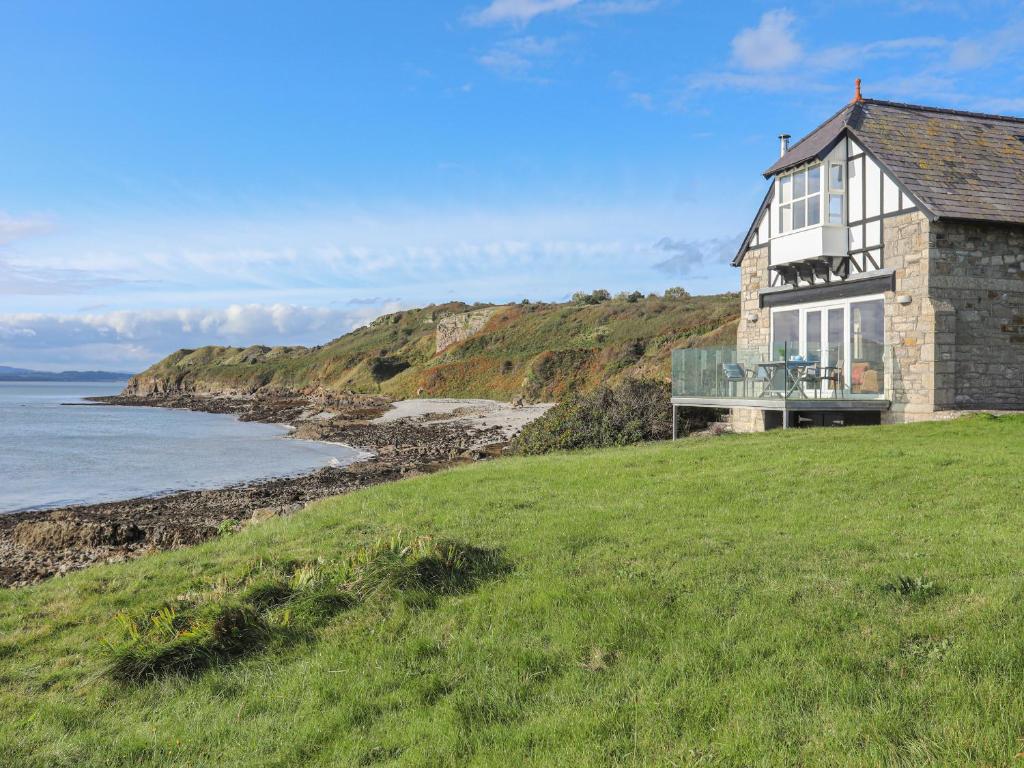 a house on a hill next to the ocean at The Old Lifeboat House in Penmon