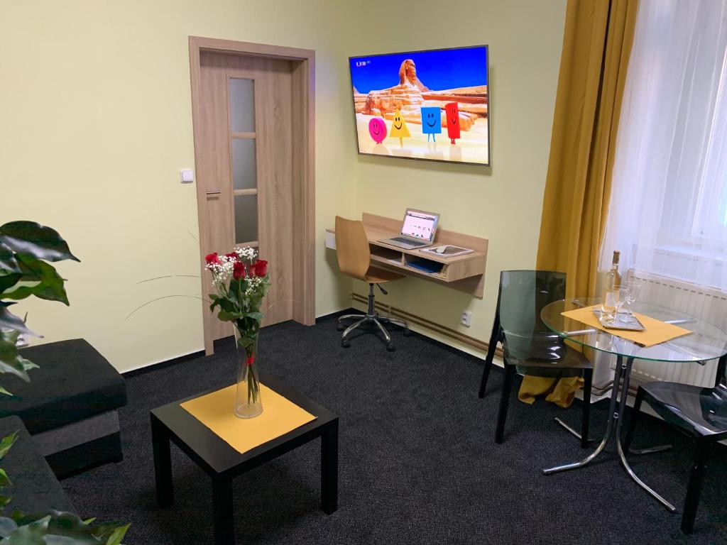 ein Büro mit einem Schreibtisch und einem Tisch mit Blumen darauf in der Unterkunft Apartmán Alesta Bruntál in Bruntál