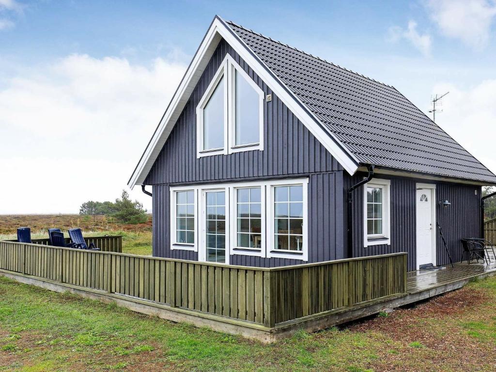 a small black house with a wooden fence at 6 person holiday home in L s in Læsø