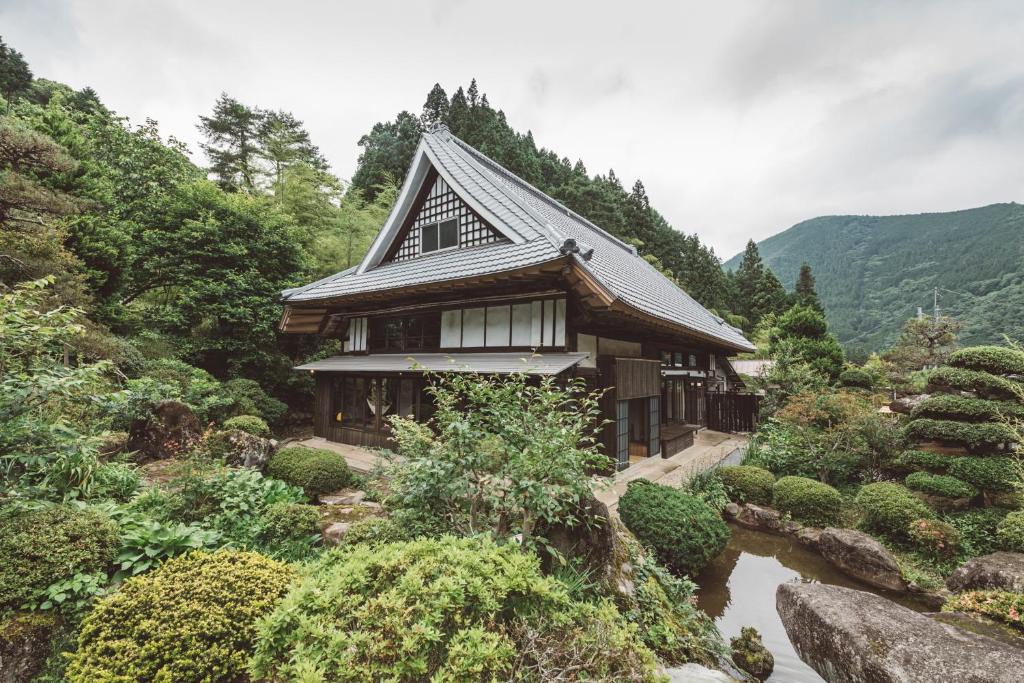 une maison sur le flanc d'une montagne à côté d'une rivière dans l'établissement NIPPONIA Kosuge Village, à Kosuge