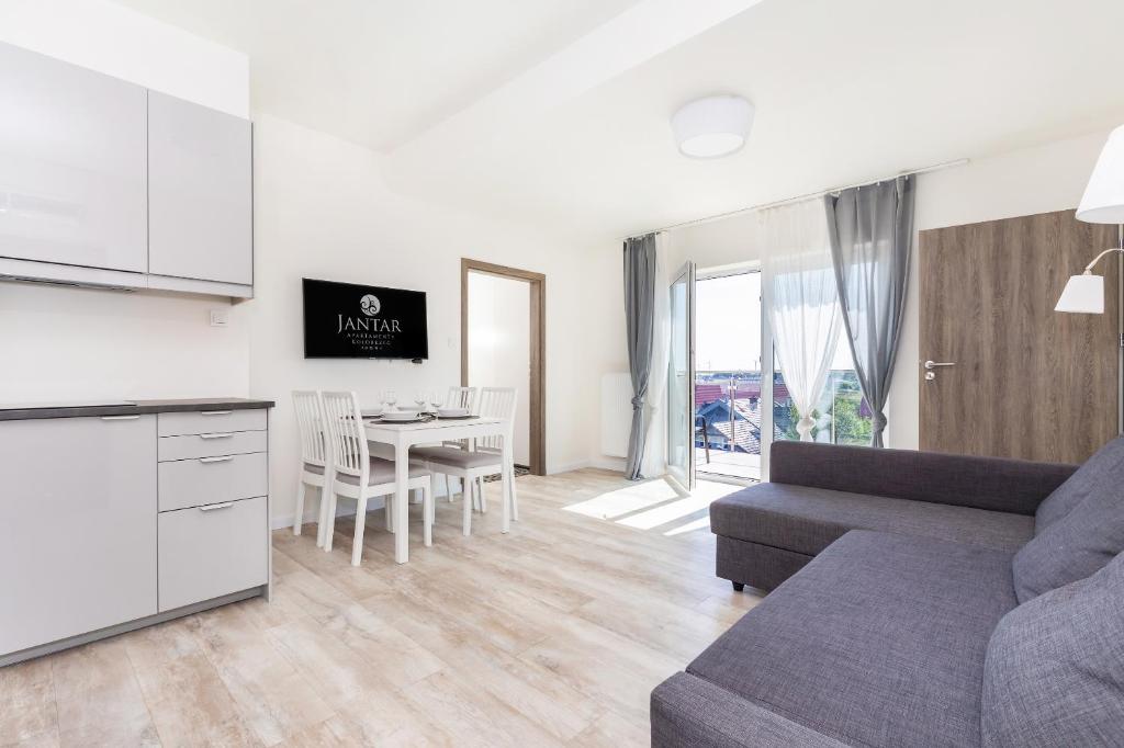 ein Wohnzimmer mit einem Sofa und einem Tisch in der Unterkunft Jantar Apartamenty - 5 Mórz Sianożęty in Sianożęty