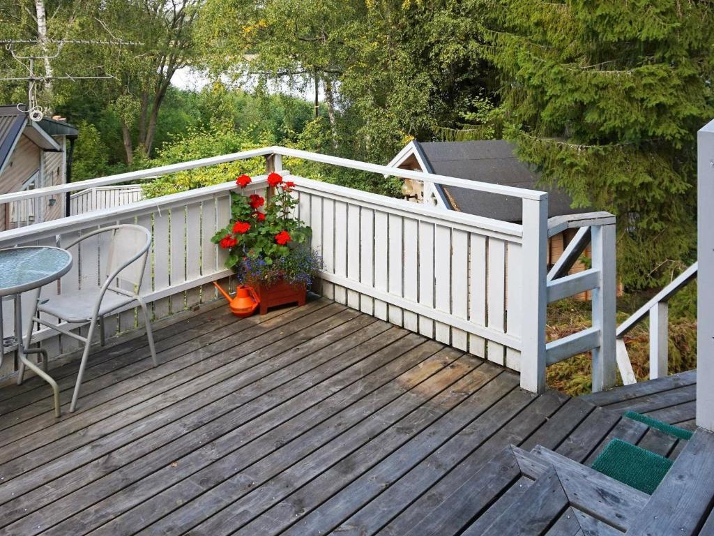 una terraza de madera con una mesa y flores. en 4 person holiday home in EKER, en Ekerö