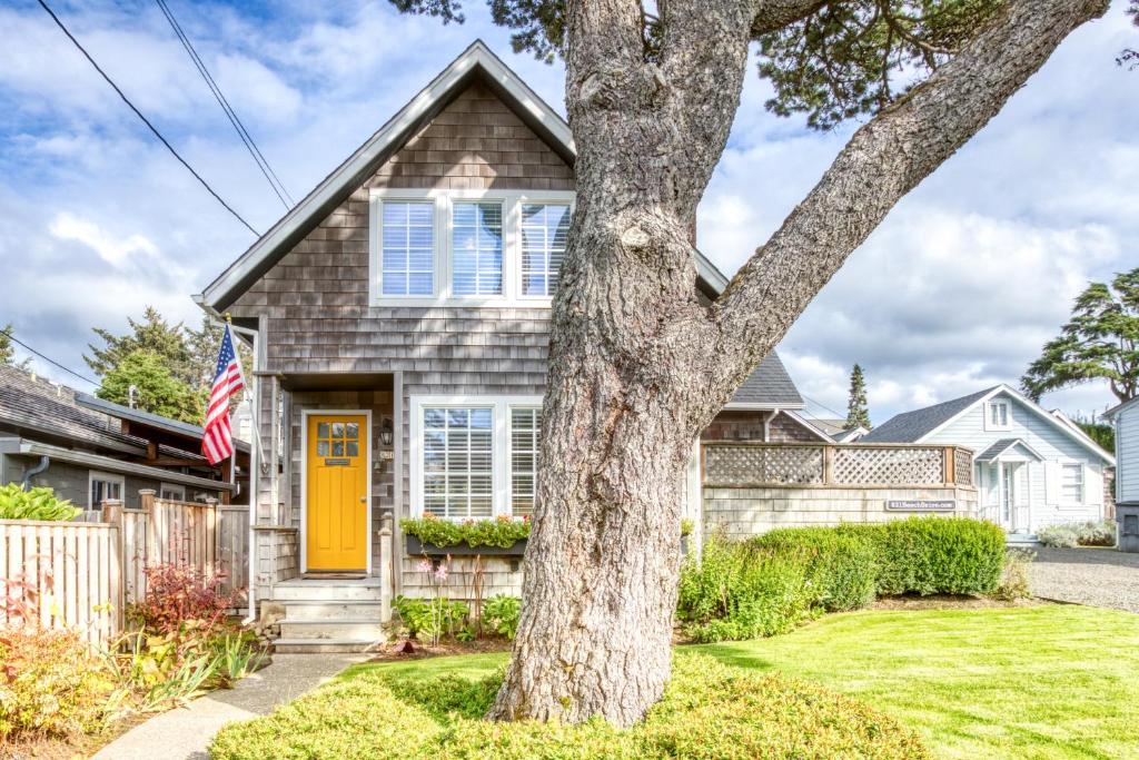 a house with a yellow door and a tree at Seaside Classic Cottage in Seaside