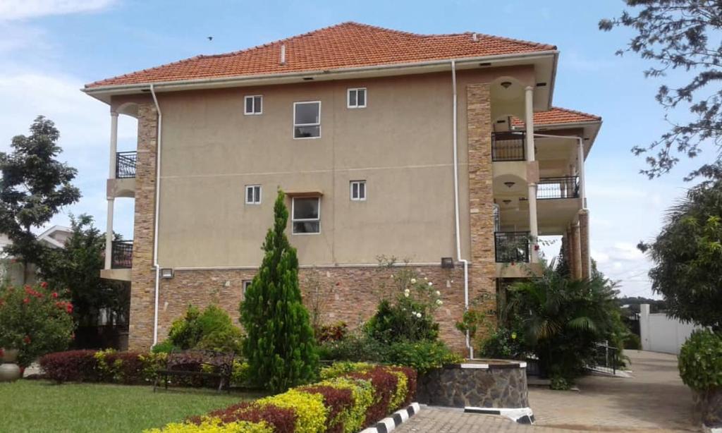 a large apartment building with a garden in front of it at RoseVilla Hotel in Arua
