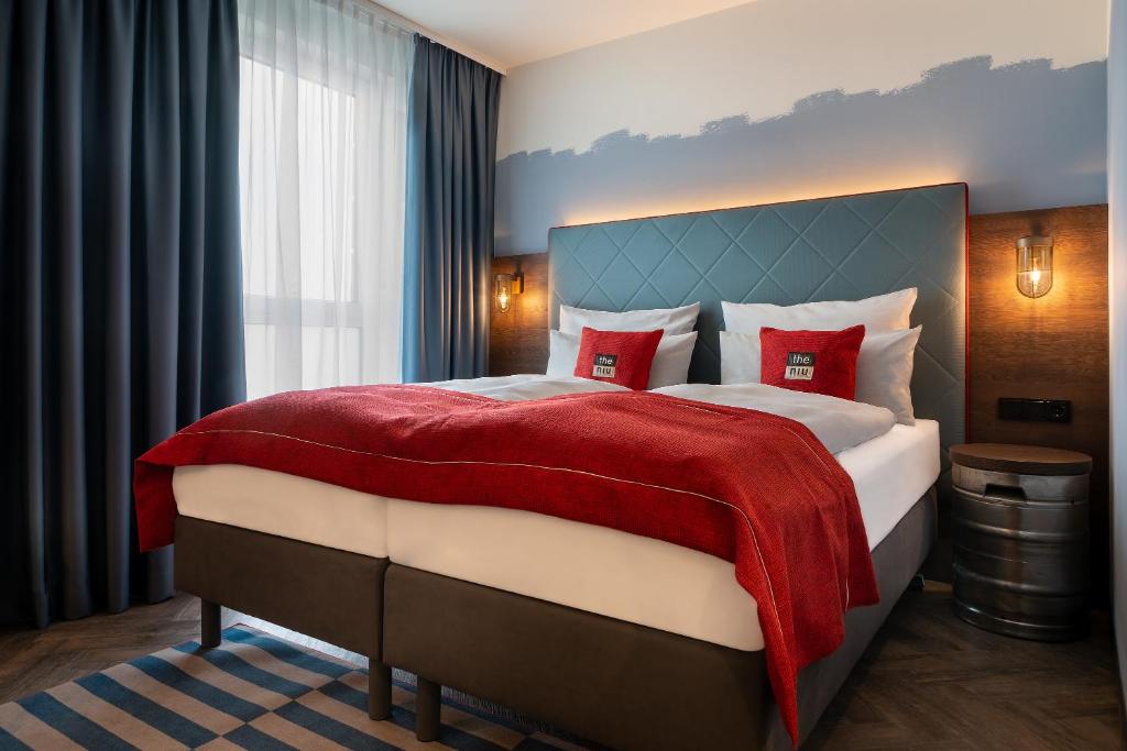 a bedroom with a large bed with red pillows at the niu Keg in Hamburg