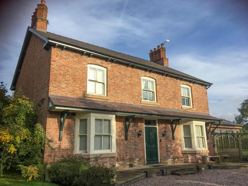 uma velha casa de tijolos com uma porta verde em Hollies Farm B&B em Wrexham