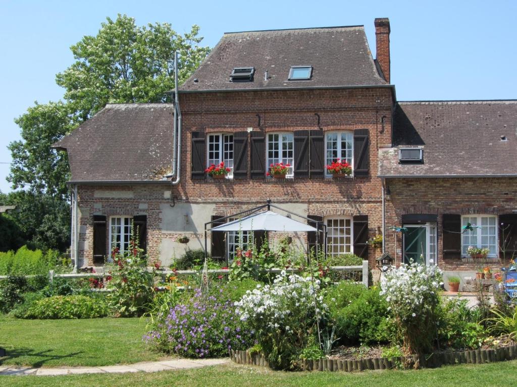 ein altes Backsteinhaus mit Blumen im Hof in der Unterkunft Le Moulin de l`Epinay in Sainte-Beuve-en-Rivière