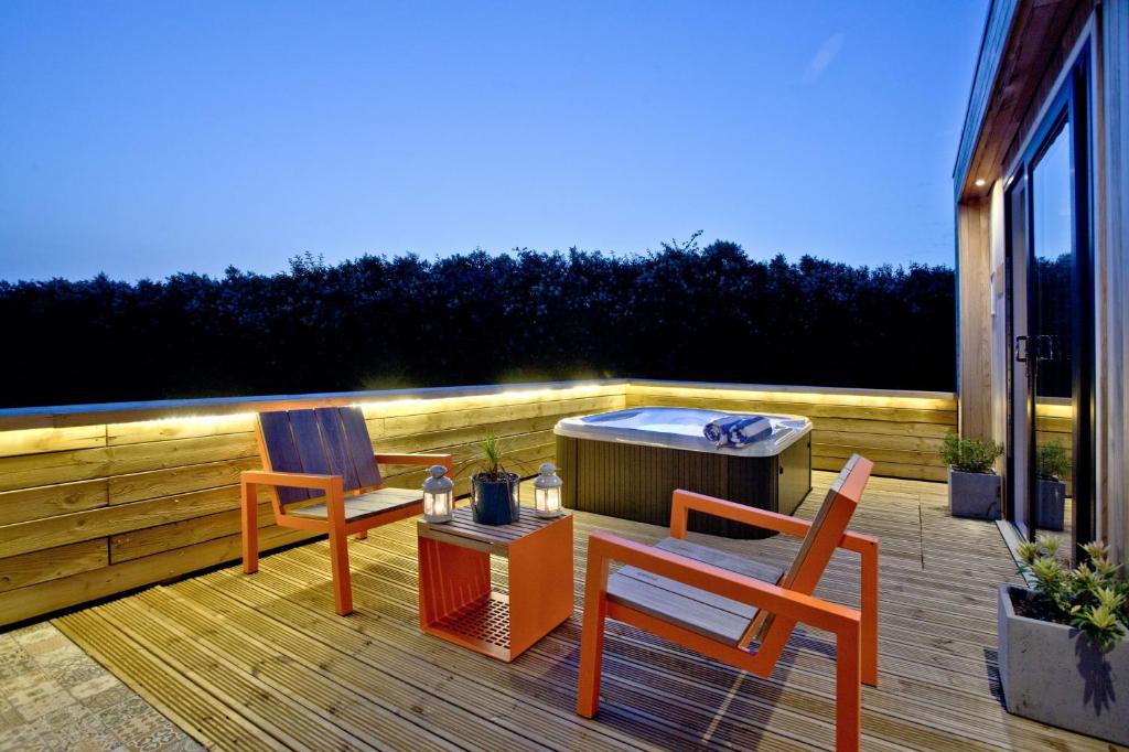 2 sedie e un tavolo su una terrazza con vasca idromassaggio di Combe Hay, Strawberryfield Park, Cheddar a Cheddar