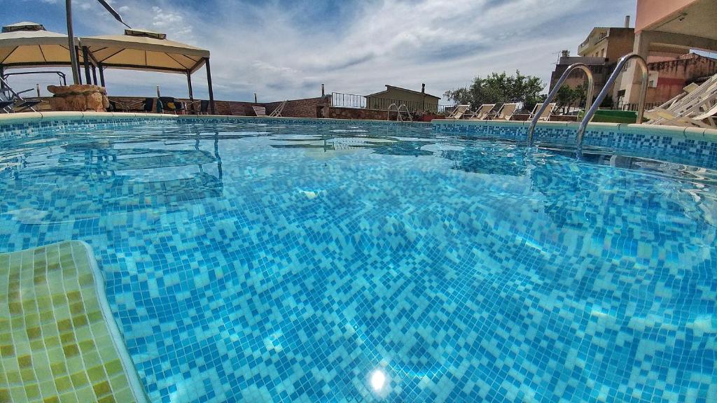 una gran piscina azul con sillas y sombrilla en Hotel Meridiana, en Arbus