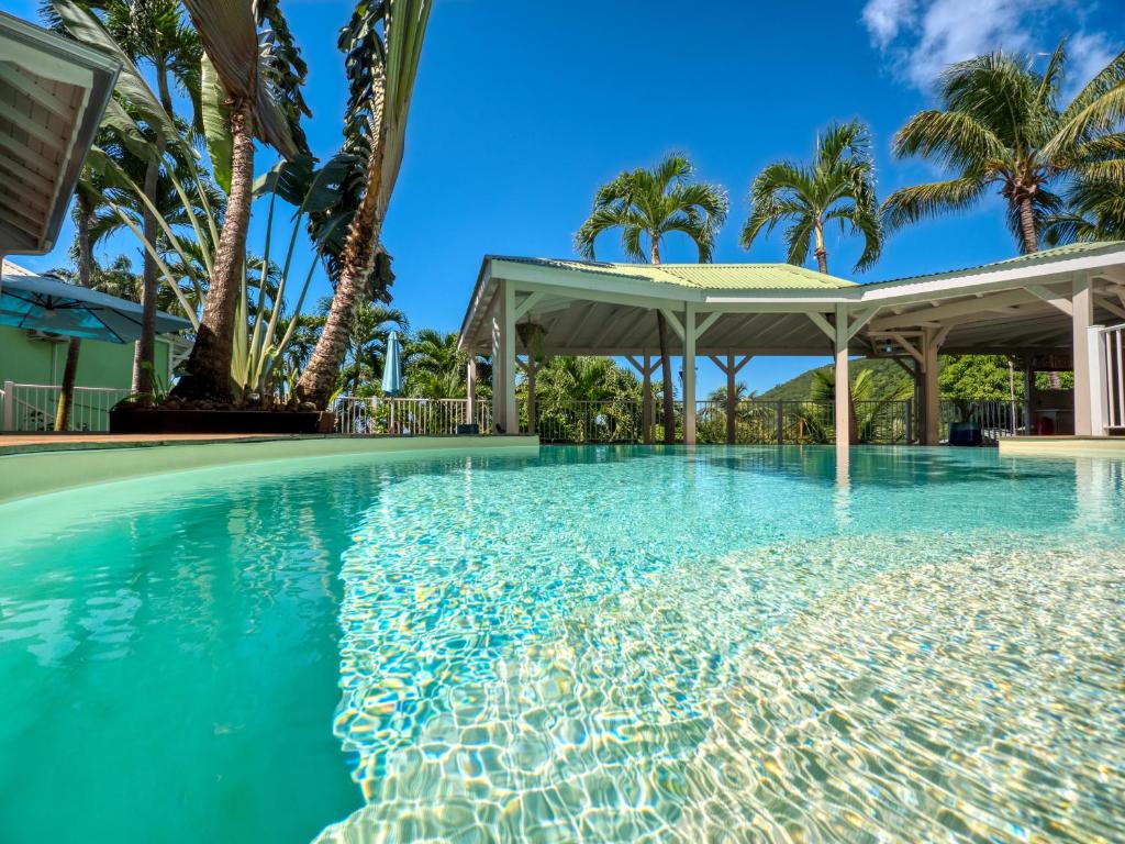 a swimming pool with a gazebo and palm trees at Lodge Coco in Deshaies