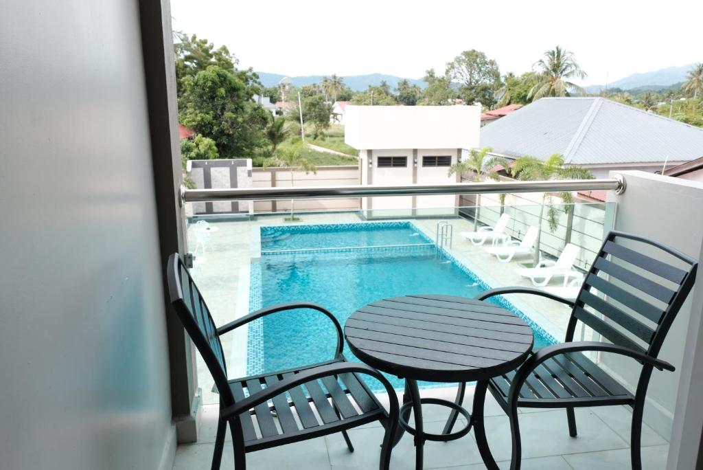 a balcony with a table and chairs and a swimming pool at Aneeda Inn in Pantai Cenang