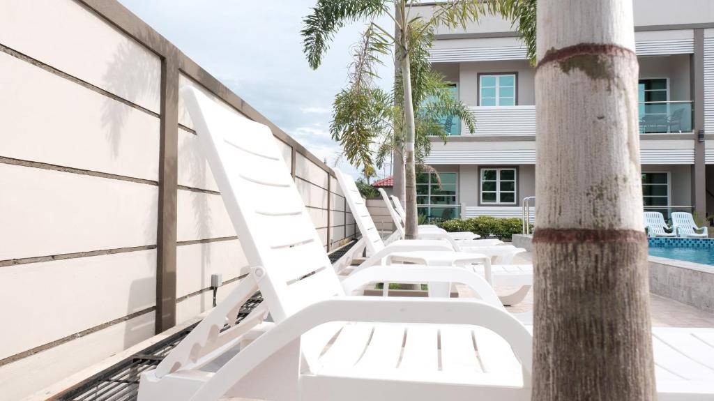 a row of white lounge chairs on the balcony of a building at Aneeda Inn in Pantai Cenang