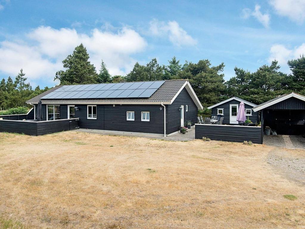 a black house with a solar roof on a yard at 7 person holiday home in Bl vand in Blåvand