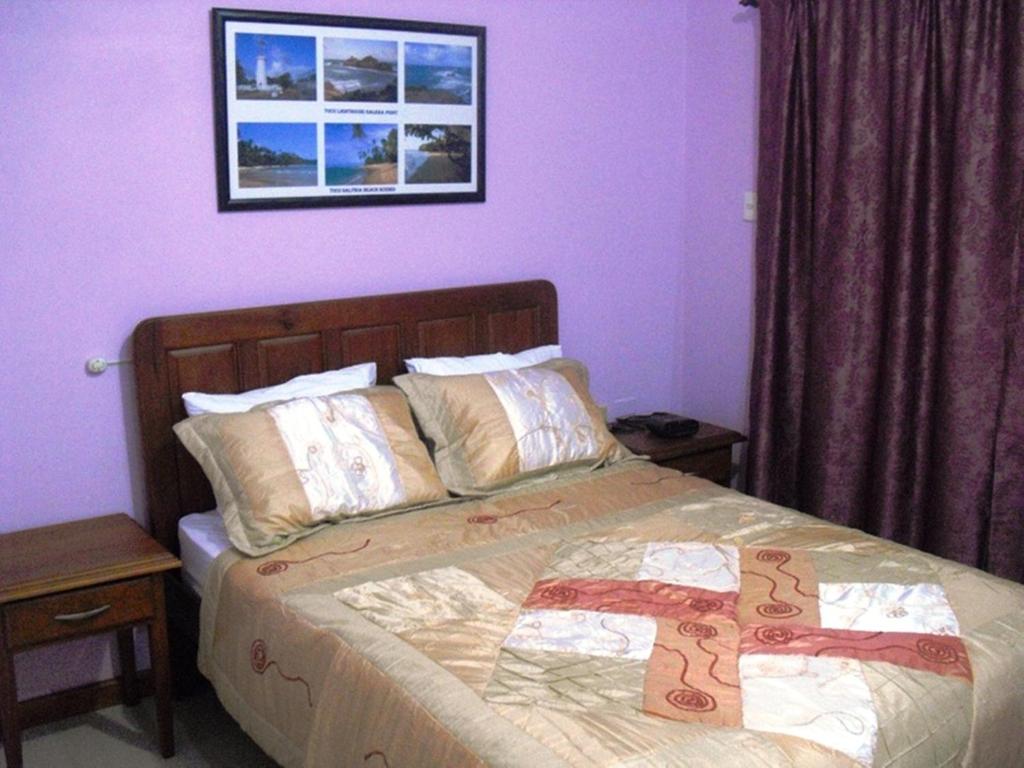 um quarto com uma cama grande e paredes roxas em Piarco Village Suites em Piarco
