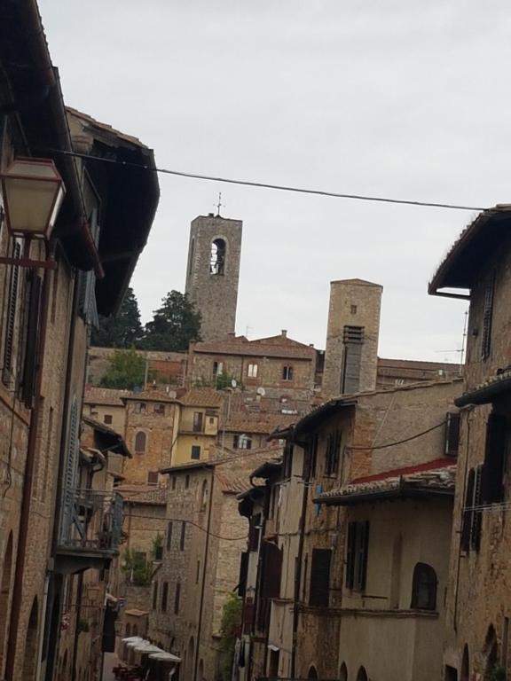 an alley with buildings and a clock tower in the background at Il Nido Di Anna in San Gimignano