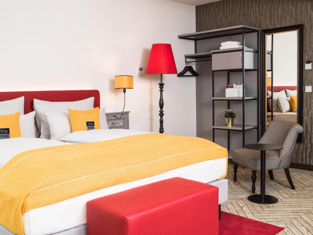 ein Schlafzimmer mit einem großen Bett und einem roten Stuhl in der Unterkunft the niu Franz in Wien