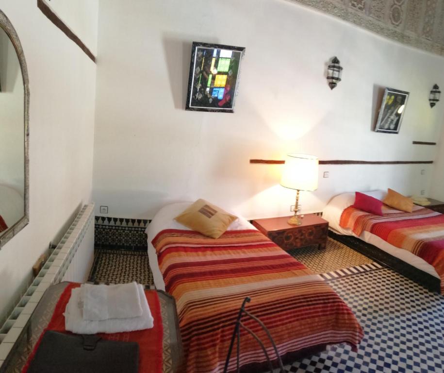 a hotel room with two beds and a lamp at Dar Ines in Moulay Idriss Zerhoun