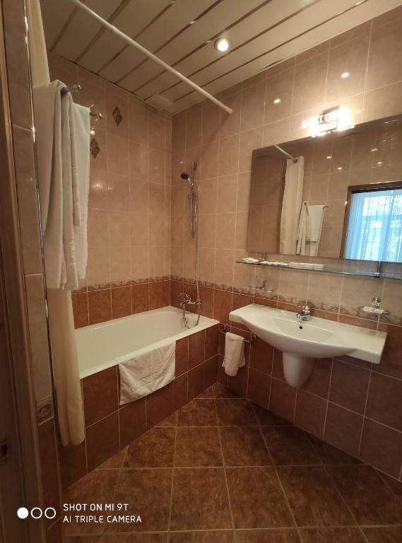 bagno con 2 lavandini, vasca e specchio di Derzhavniy Hotel a Mosca