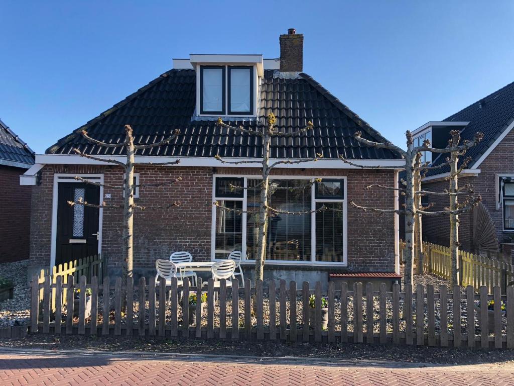 ein Backsteinhaus mit einem Zaun davor in der Unterkunft Frysk Hûs in Paesens