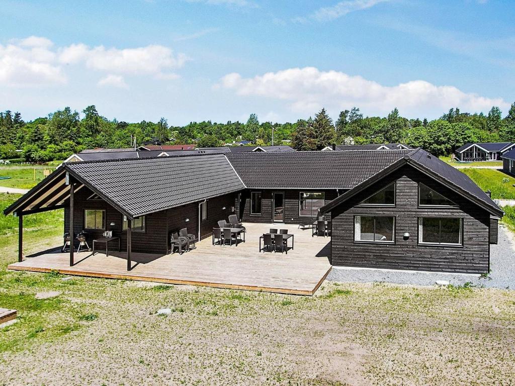 a large house with a wooden deck in a field at 20 person holiday home in Vejby in Vejby