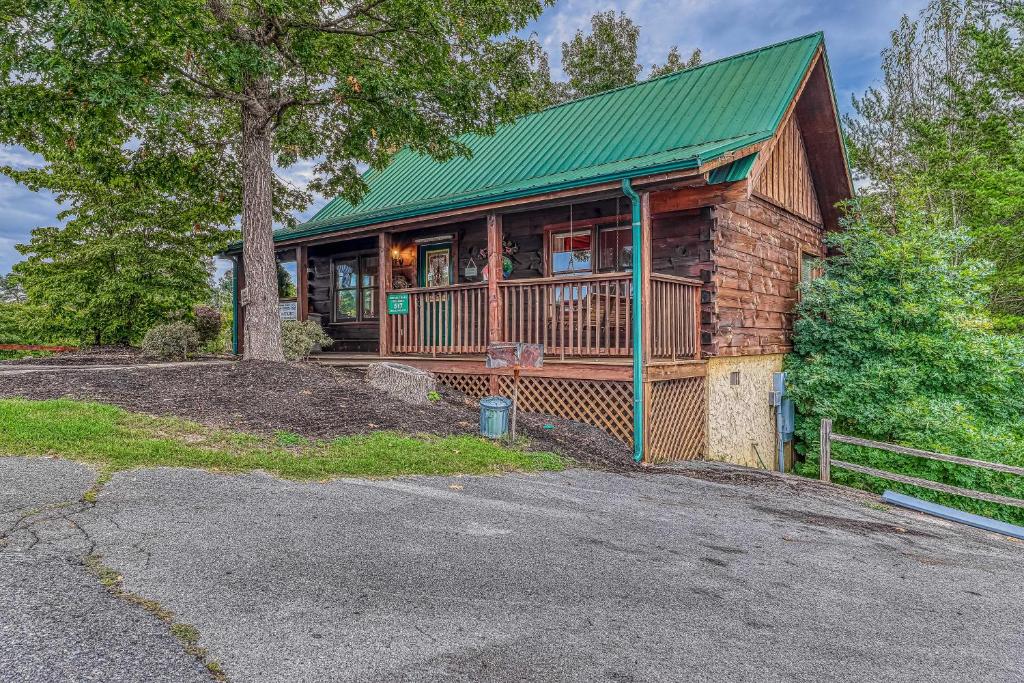 a log cabin with a green roof and a driveway at Snuggle Bear Hideaway in Pigeon Forge